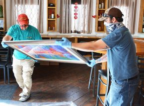 ABOVE: Workers prepare Arthur Miller’s artwork for shipment to a U.S. Embassy in Africa. RIGHT: Miller shows one of his works selected for display in the official residence of Sandra E. Clark, the U.S. ambassador to Burkina Fasou in West Africa.